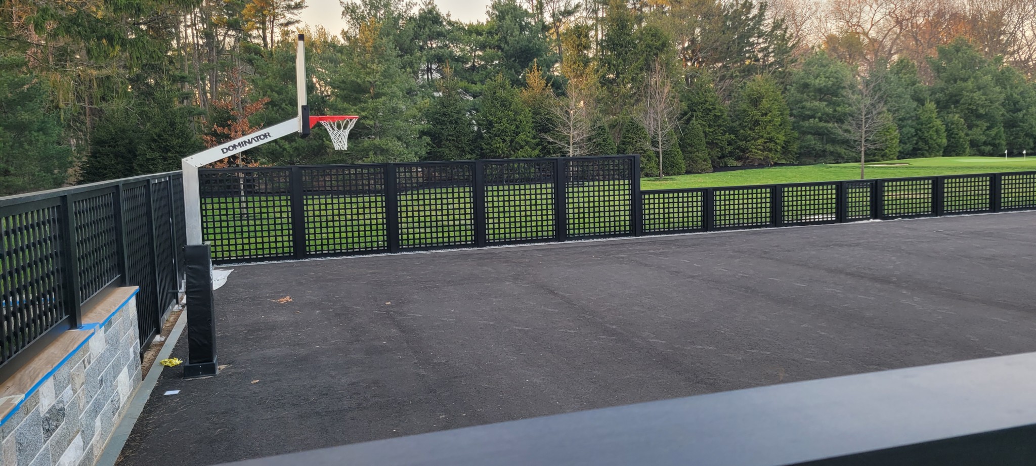 Black painted metal lattice fence panels surrounding a sport court.
