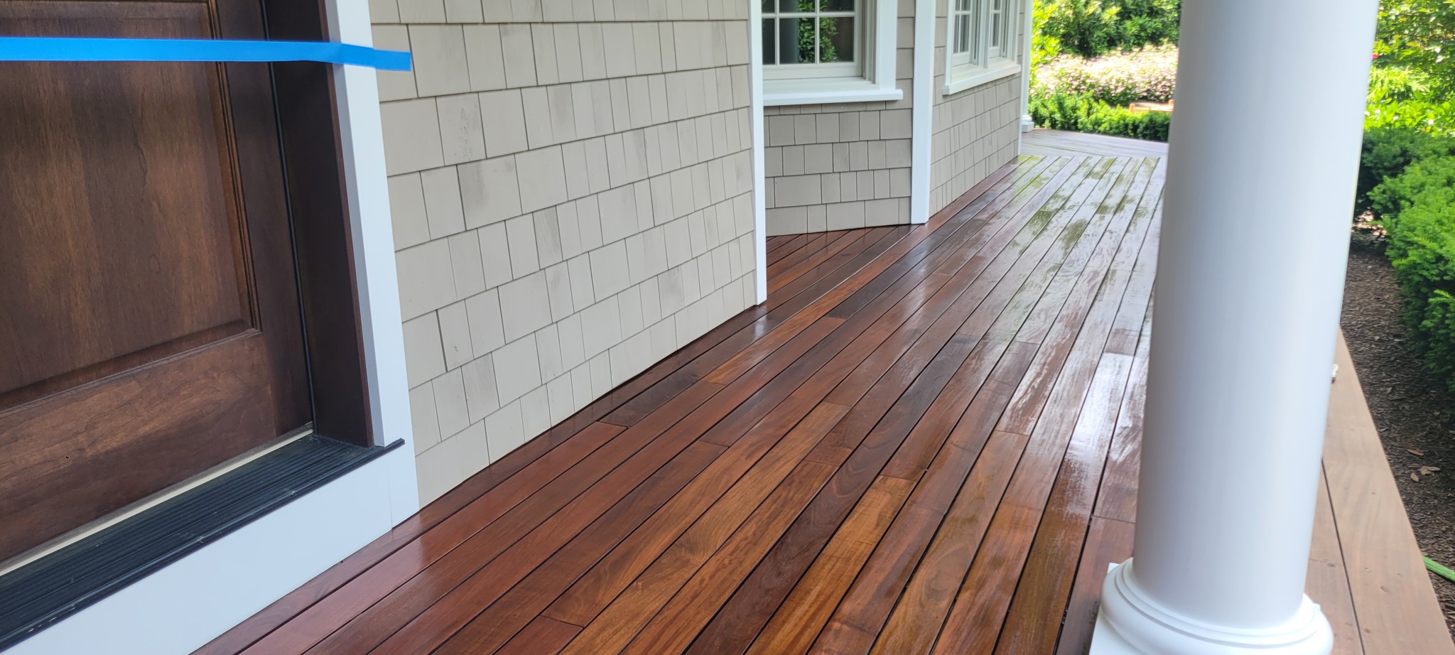Wood deck boards after staining; painted exterior trim, door frame, and column.